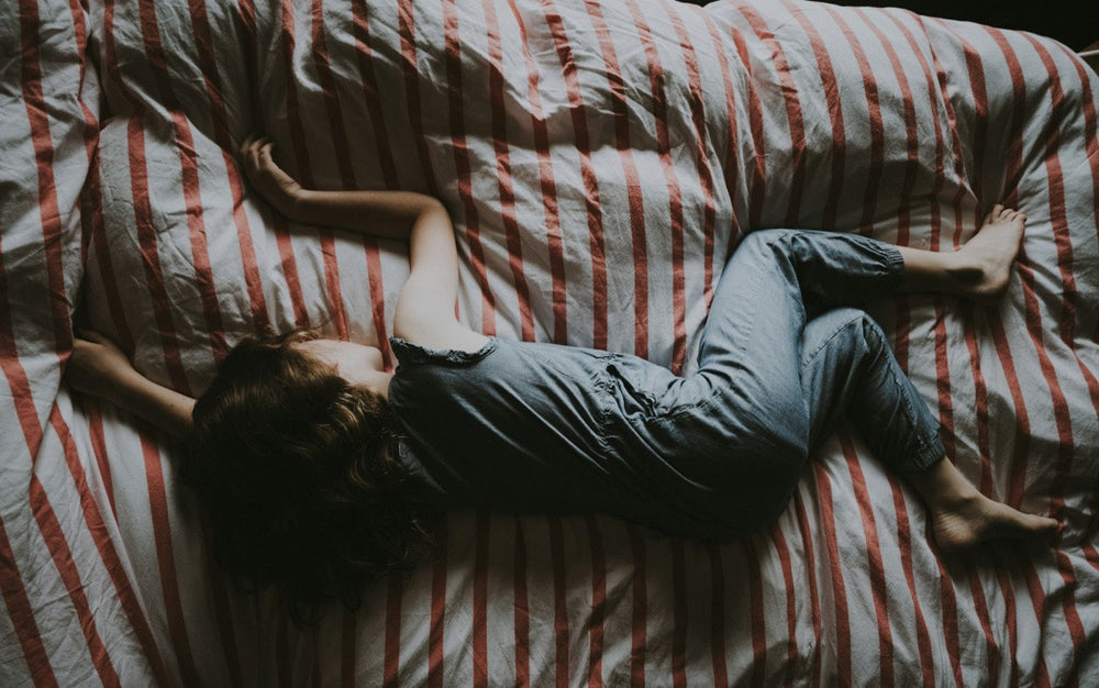 Child asleep on a bed with red and white striped bedding, seen from above